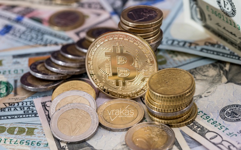 Stacked gold coins with a Bitcoin logo and American money.