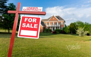 For Sale sign in front of home and a field.